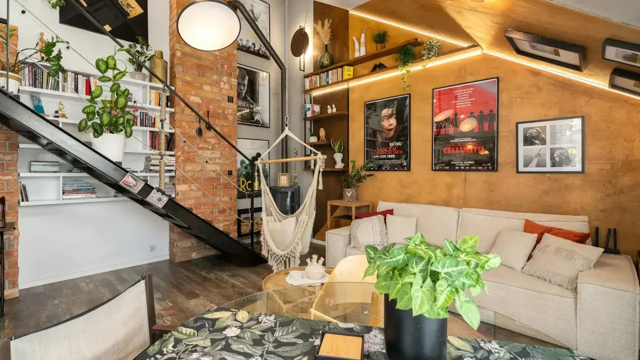 Przytulny mały pokój w stylu loft z ceglaną ścianą, metalowymi schodami, wiszącym fotelem i wygodną kanapą.