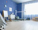 Pokój chłopca z niebieskimi ścianami ozdobionymi gwiazdkami. Wesołe kolory ścian tworzą przytulną atmosferę dla małego odkrywcy.