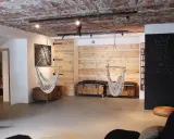 Nowoczesna aranżacja piwnicy w domu: wiszące fotele, drewniane panele, skrzynie i tablica z napisem "Keep Calm and Decore".