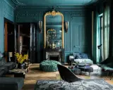 Elegancja w kolorze petrol blue: salon z bogatymi zdobieniami, złotym lustrem i nowoczesnymi meblami.