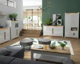 Nowoczesny salon z zielonymi ścianami, białymi meblami i drewnianymi elementami.