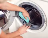 Ręce czyszczą uszczelkę pralki niebieską ściereczką. Dowiedz się, jak wyczyścić bęben pralki, aby zapewnić świeżość ubrań.