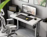 Ergonomiczne biurko do pracy przy komputerze z monitorem, klawiaturą i myszką. Obok stoi wygodny fotel biurowy i szafka z głośnikiem Marshall.