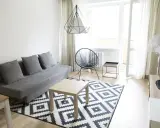 Nowoczesny salon z szarą kanapą i geometrycznym dywanem. Stylowa metamorfoza pokoju tanim kosztem.