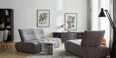 Przytulny kącik zabaw dla dziecka w salonie, z szarymi pufami i stolikiem.
