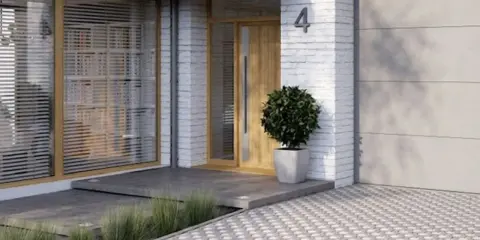 Nowoczesny wiatrołap zewnętrzny inspiracje: drewniane drzwi, betonowe schody i ozdobna trawa. Eleganckie wejście do domu.