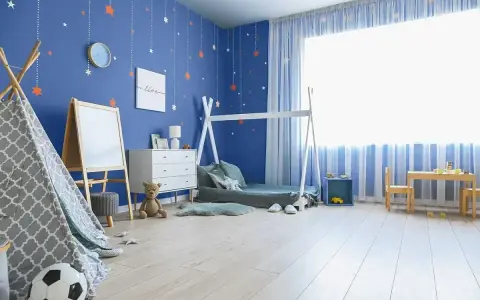 Pokój chłopca z niebieskimi ścianami ozdobionymi gwiazdkami. Wesołe kolory ścian tworzą przytulną atmosferę dla małego odkrywcy.