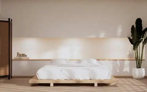 Spokojna sypialnia w stylu japandi z niskim łóżkiem, bambusowym parawanem i dużą rośliną.