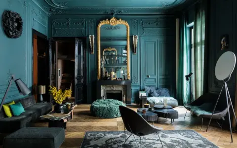 Elegancja w kolorze petrol blue: salon z bogatymi zdobieniami, złotym lustrem i nowoczesnymi meblami.