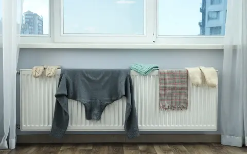 Jak zasłonić kaloryfer pod oknem? Ubrania suszą się na grzejniku, tworząc naturalną osłonę.