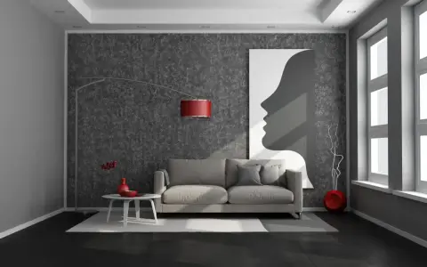 Nowoczesny salon z ciemną podłogą, szarą kanapą i abstrakcyjnym obrazem.