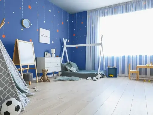 Pokój chłopca z niebieskimi ścianami ozdobionymi gwiazdkami. Wesołe kolory ścian tworzą przytulną atmosferę dla małego odkrywcy.
