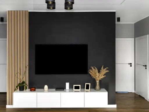 Nowoczesny salon z czarną ścianą TV, białym meblem i drewnianą okładziną.