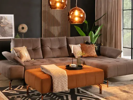 Elegancki salon z sofą w kolorze taupe. Idealnie komponuje się z pomarańczowym pufem, miedzianymi lampami i złotymi dodatkami.