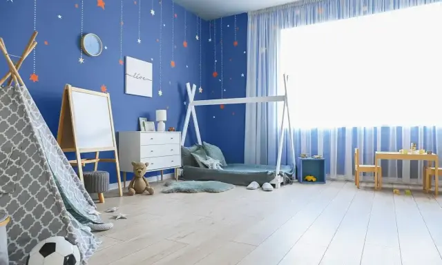 Pokój chłopca z niebieskimi ścianami ozdobionymi gwiazdkami. Wesołe kolory ścian tworzą przytulną atmosferę dla małego odkrywcy.