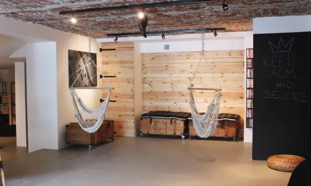 Nowoczesna aranżacja piwnicy w domu: wiszące fotele, drewniane panele, skrzynie i tablica z napisem "Keep Calm and Decore".