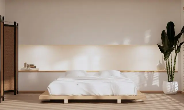 Spokojna sypialnia w stylu japandi z niskim łóżkiem, bambusowym parawanem i dużą rośliną.