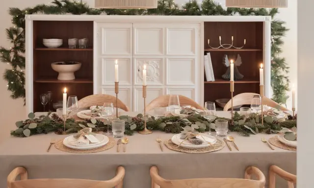 Elegancko nakryty stół na Boże Narodzenie z girlandą z gałązek, świecami i złotymi sztućcami. Inspiracja, jak udekorować stół na Boże Narodzenie.