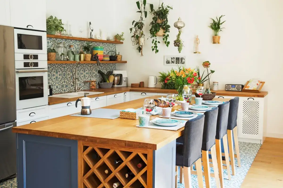 Przytulna kuchnia boho vintage z wyspą i winoteka. Mnóstwo roślin i kolorowe akcenty tworzą ciepłą atmosferę.
