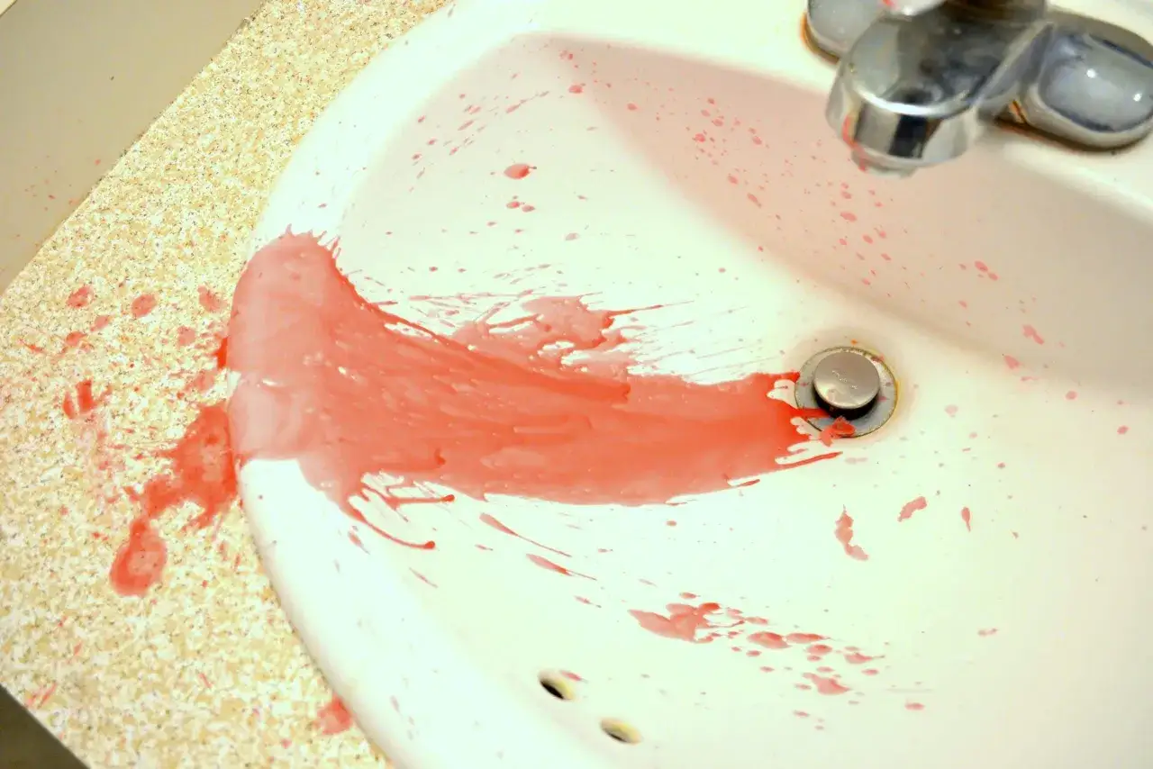 Rozlany czerwony wosk w umywalce. Jak zmyć wosk? Gorąca woda i detergent powinny pomóc.