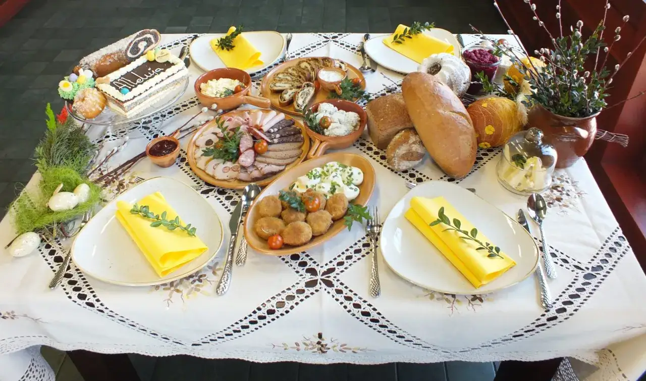 Tradycyjna dekoracja stołu wielkanocnego: babka, makowiec, wędliny, jajka, chleb i bazie.