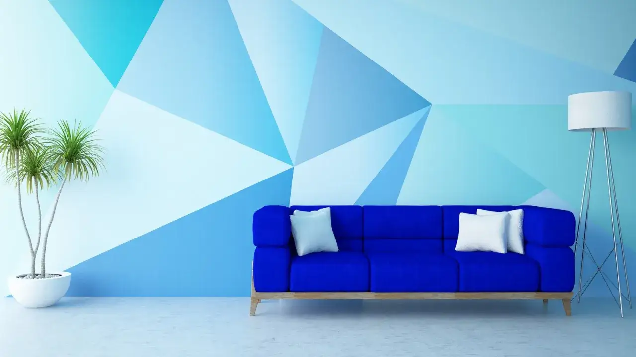 Niebieska sofa i roślina stoją przy ścianie z geometrycznym wzorem. Malowanie ścian od okna czy do okna? Tu ściana jest dziełem sztuki.