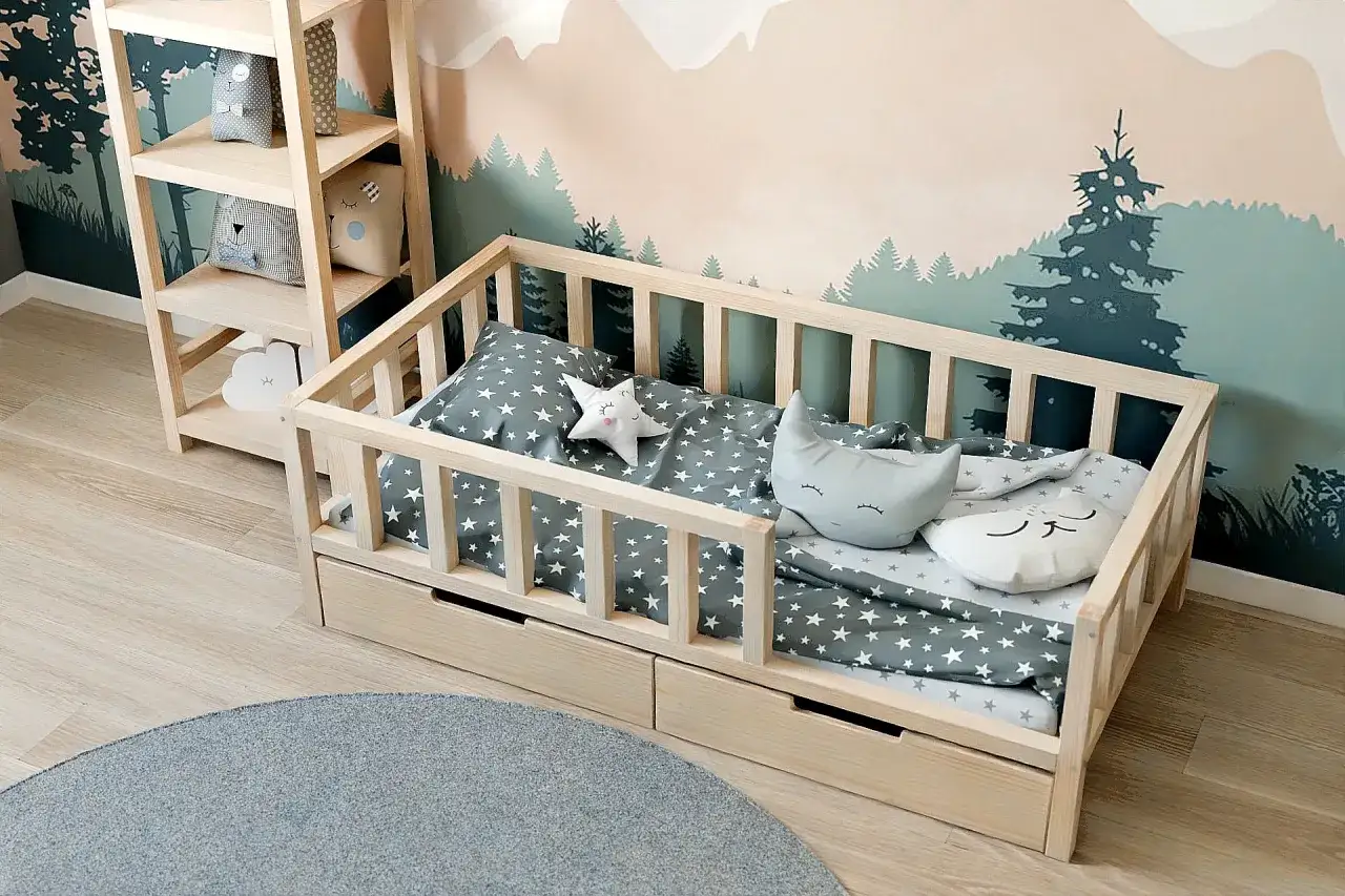 Drewniane łóżeczko dla dziecka z szufladami, pościelą w gwiazdki i poduszkami w kształcie księżyca i gwiazdy. Idealne pytanie: jakie łóżeczko dla dziecka?