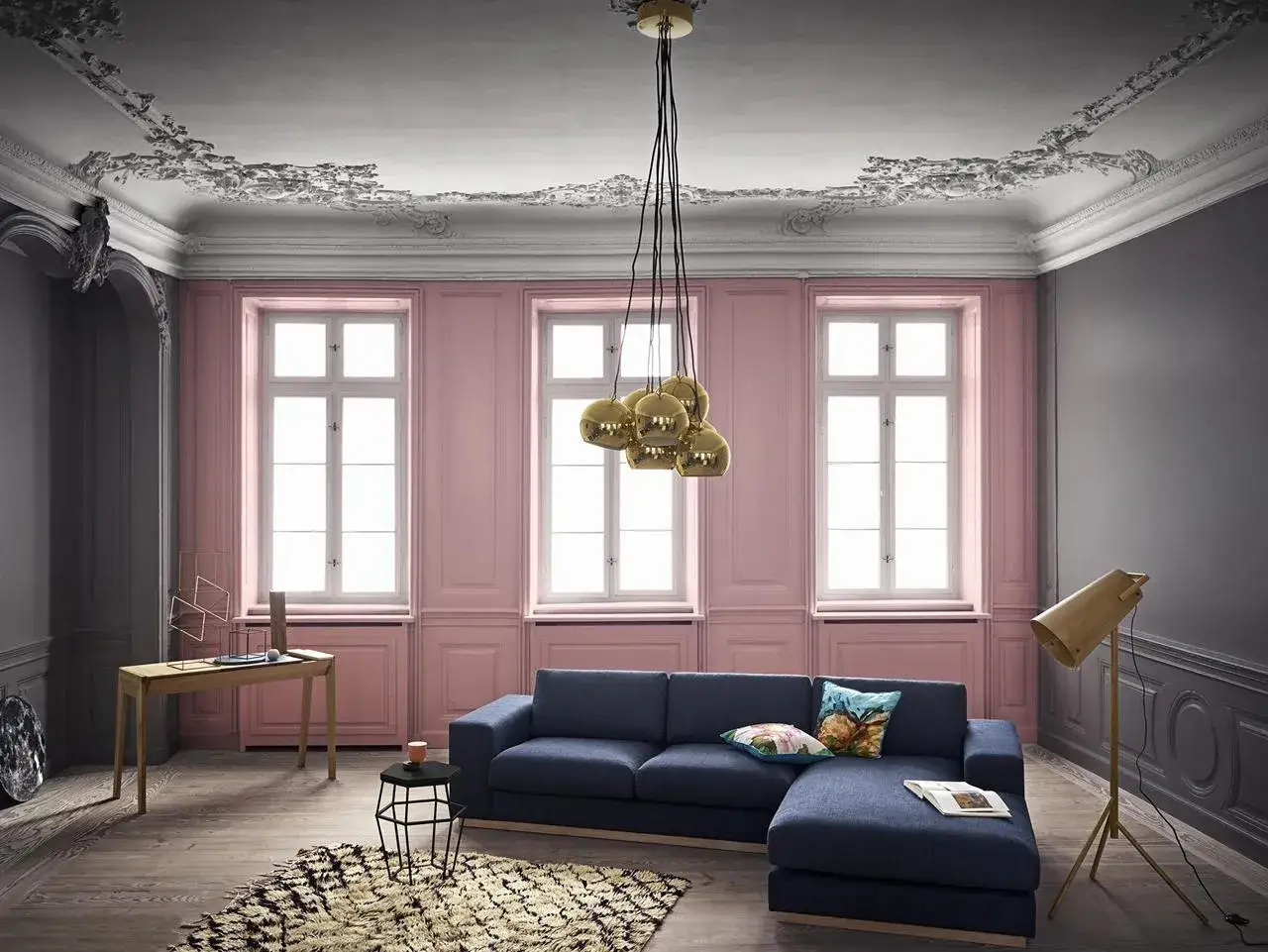 Elegancki salon z granatową sofą i dywanem. Kontrast między szarymi a różowy kolor ścian dodaje wnętrzu charakteru.