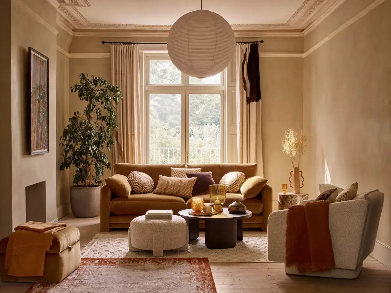 Przytulny salon z kanapą w kolorze musztardowym, pufą i fotelem w odcieniach beżu. Modne kolory mebli tworzą ciepłą atmosferę.