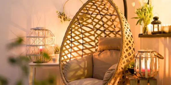 Przytulny kącik z fotelem wiszącym i lampionami w salonie. Ciepłe światło świec tworzy nastrojowe aranżacje.